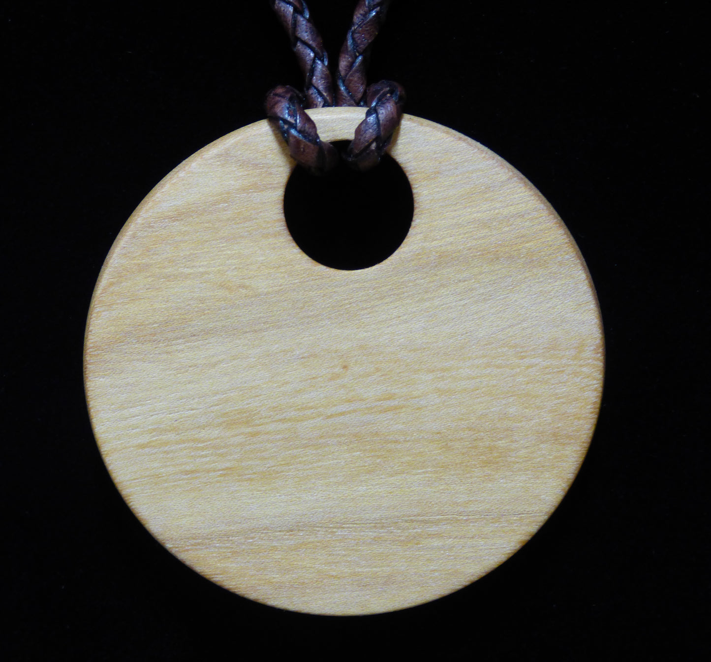 Wooden pendant with a leather cord on a black background