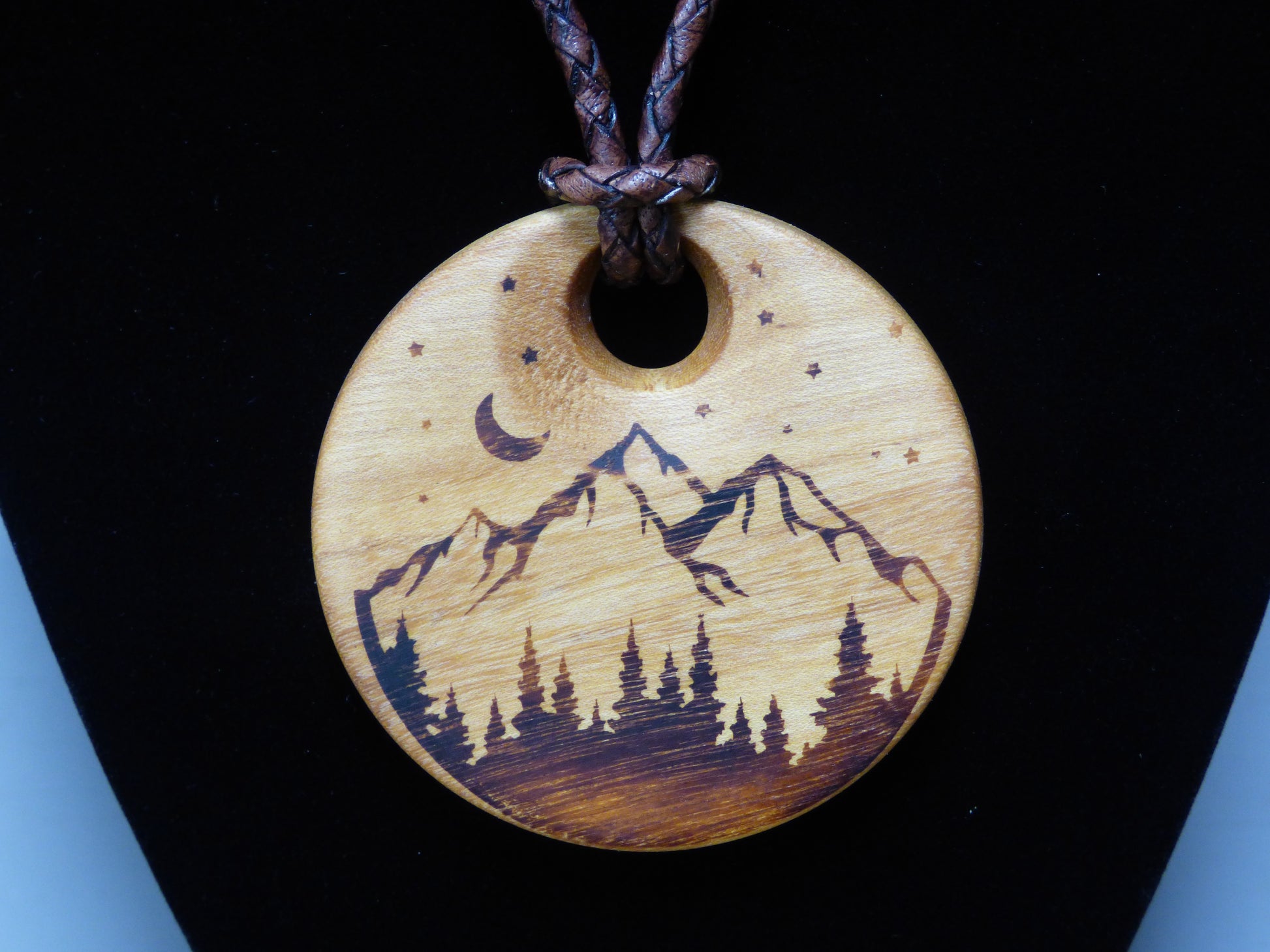 Wooden pendant with mountain and moon design on a black background