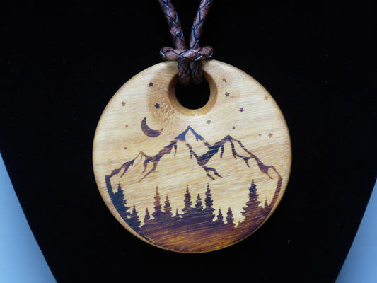 Wooden pendant with mountain and moon design on a black background
