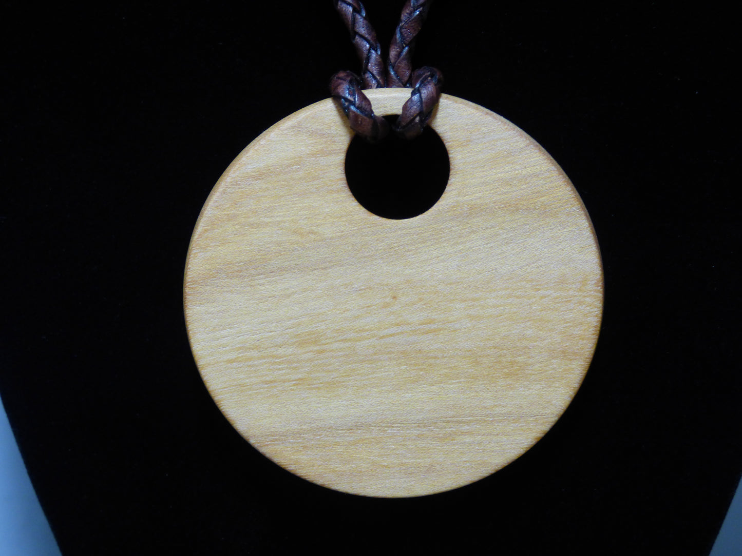 Back of wooden pendant against a black background
